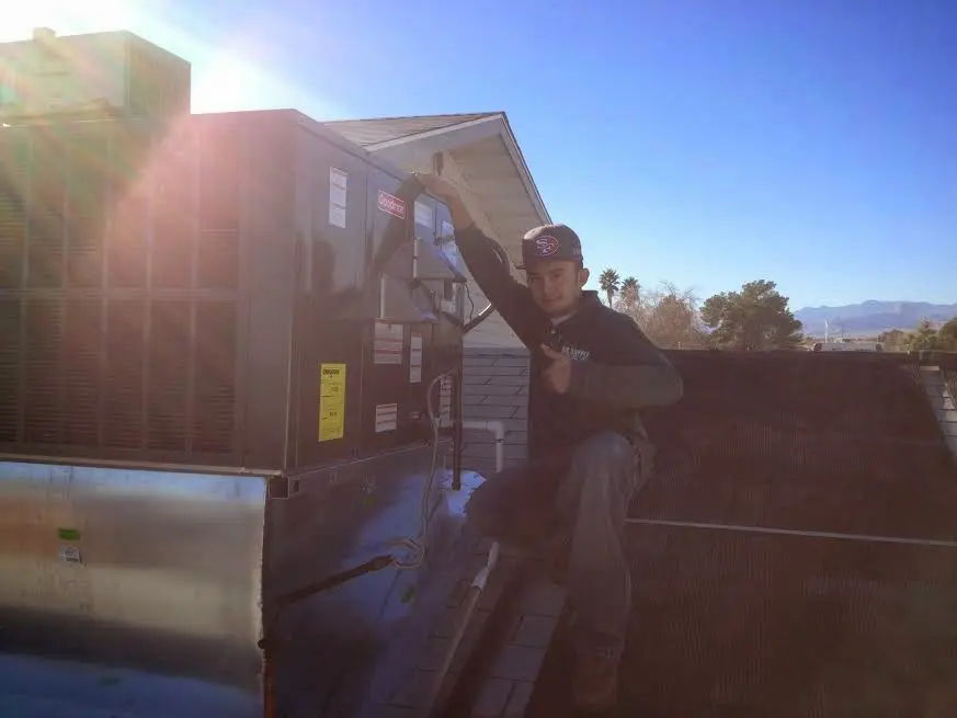 HVAC technician performing AC Tune-Up on a rooftop unit in Ayer
