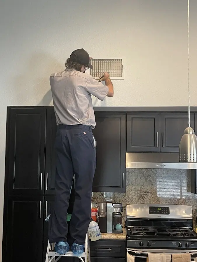Technician inspecting an air vent during HVAC service in Ayer